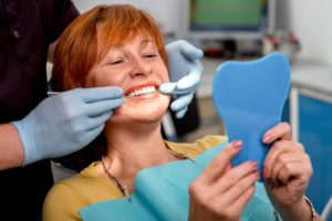 woman looking in mirror dental implant